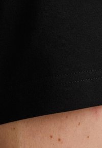 Tela de algodón elástica negra en el dobladillo, con una textura suave y costuras finas. Primer plano de un diseño ajustado, minimalista y sin costuras.