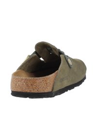 Sabot en suède vert olive à enfiler, avec sangle réglable, semelle en liège, semelle noire et détail de boucle en métal.