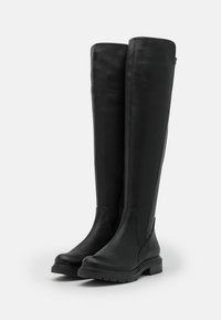 Botas de cuero negras hasta la rodilla con una textura suave, puntera redonda, tacón bajo en bloque y paneles laterales elásticos para facilitar su uso.