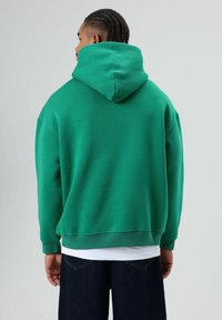 Groene hoodie met een relaxte pasvorm, geribbelde manchetten en een brede halslijn, gemaakt van zachte, gestructureerde stof.