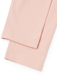 Lichtroze leggings gemaakt van zachte geribde stof, met een klein logo-detail nabij de zoom en afgewerkt met een nette steek op de randen.