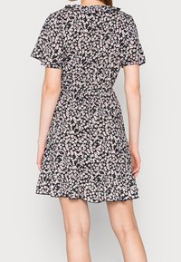 Robe noire à fleurs avec des manches courtes, présentant une taille ajustée, une jupe évasée et un ourlet à volants. Petits motifs de fleurs roses et blanches partout.