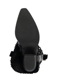 Zapato negro de tacón con suela de goma texturizada, parte trasera abierta y parte superior sintética decorativa de estilo encaje. Cuenta con una correa con hebilla.