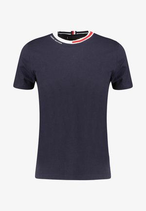 T-shirt bleu marine à manches courtes avec un col rond présentant un bord blanc et rouge et un petit texte blanc "Tommy Hilfiger" près du col.