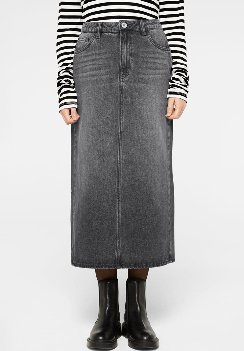 Dunkelgrauer Jeans-Maxikleid, mit vorderen Taschen, geradem Schnitt und Gürtelschlaufen. Kombiniert mit schwarzen Knöchelstiefeln und einem gestreiften Oberteil.