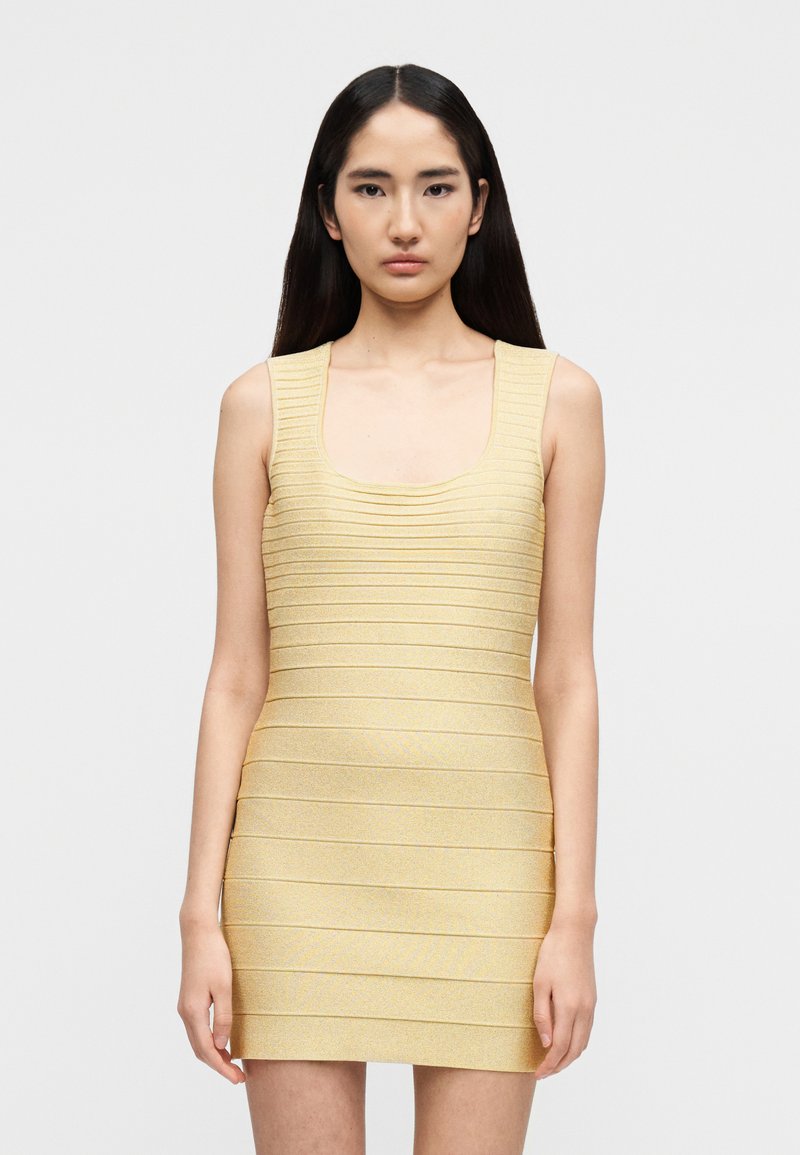 Κίτρινο πλεκτό φόρεμα με τετράγωνη λαιμόκοψη και ριγέ υφή. Διαθέτει εφαρμοστή γραμμή και μανίκια χωρίς μανίκια. Λεία υφή υφάσματος με λάμψη.