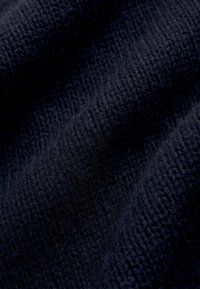 Țesătură texturată de culoare bleumarin cu o suprafață moale, ușor pufoasă, care prezintă un model subtil de țesătură și ondulații blânde.