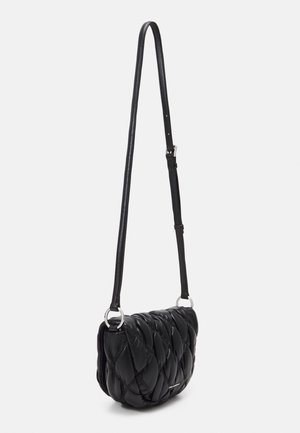Borsa a tracolla in pelle nera trapuntata con lunga tracolla regolabile e anelli metallici argentati su sfondo chiaro.