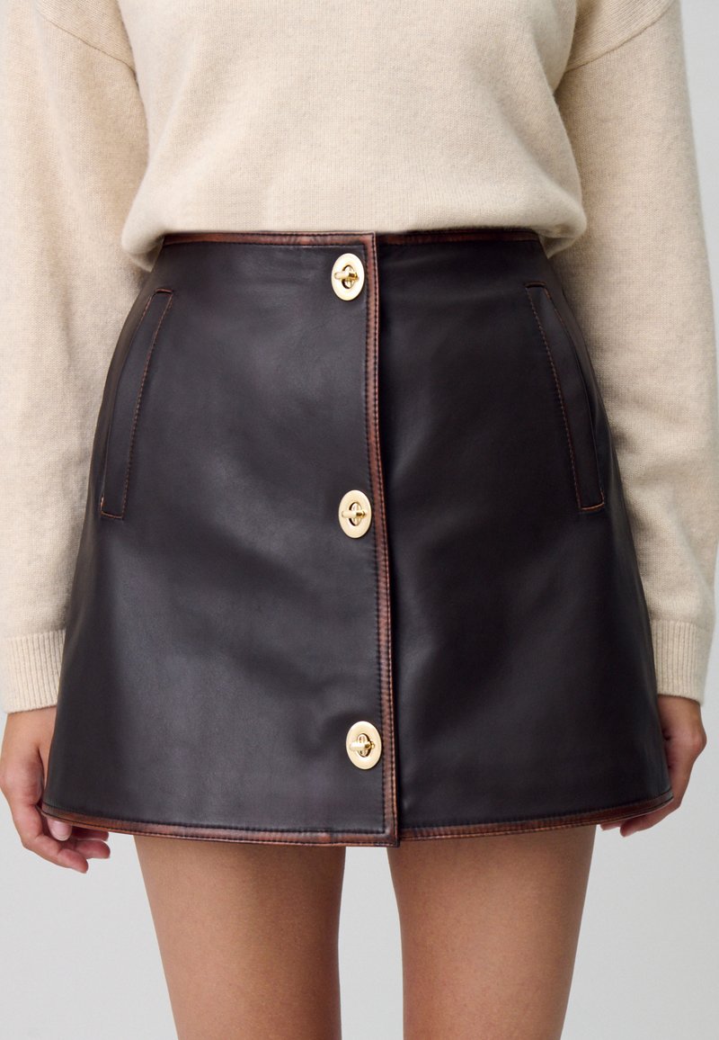 Gonna a vita alta in pelle marrone con bottoni e accessori dorati, dotata di tasche frontali e cuciture a contrasto, design svasato su misura.