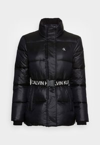 Černá puffer bunda s vysokým límcem, stahovaným pasem pomocí pásku s logem "CALVIN KLEIN", s prošívan�ými sekcemi a bočními kapsami.