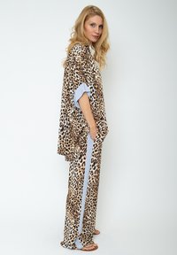 Zestaw dresowy w panterkę, składający się z luźnej bluzki z szerokimi rękawami oraz dopasowanych spodni z paskowymi akcentami i kieszeniami. Wykonany z miękkiego materiału.