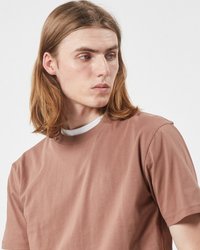 Brun kortärmad T-shirt med rund halsringning, slät textur och avslappnad passform. Bärs över en vit skjorta med hög krage.