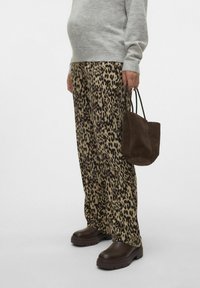 Hlače s leopard uzorkom u bež i smeđoj boji, siva džemper, smeđa suknja torba, i tamno smeđe cipele s debelim potplatom.
