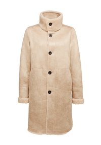 Beige fårskinnsjacka med hög krage, framknappar, två sidofickor och texturerade ärmslut. Slät ytteryta med mjukt innerfoder.