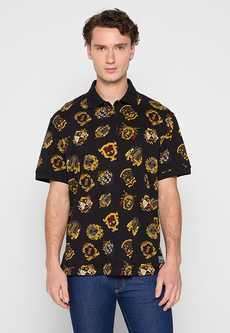 Schwarzes Poloshirt mit goldenen Emblem-Muster. Mit Kragen und kurzen Ärmeln gestaltet. Der Stoff fühlt sich glatt und leicht an.