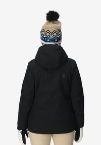 Giacca nera impermeabile con cappuccio, con un logo sul retro. Abbinata a un cappello di lana beige con una fascia a motivi neri e blu.