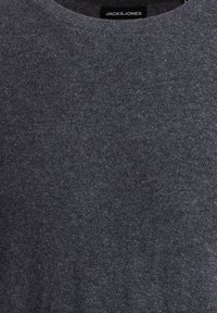 Mörkgrå stickad tröja med en bekväm rundhalsning och mjuk textur. Har en liten etikett nära halslinningen.