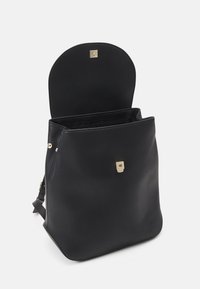 Czarny skórzany plecak z zaokrąglonym dnem, złotymi elementami metalowymi i otwartym wnętrzem do przechowywania. Charakteryzuje się prostymi liniami i minimalnym zdobieniem.