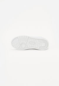 Fehér sneaker talp texturált gumifelülettel. Kör alakú logóval és jellegzetes talpmintázattal rendelkezik a tapadásért és az erősebb fogásért.