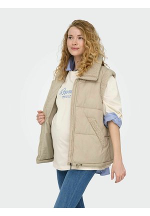 Beige gewatteerd vest met een gestructureerde kraag, voorzakken en een ritssluiting. Draagt over een lichtgekleurde shirt met een blauw gestreepte kraag.