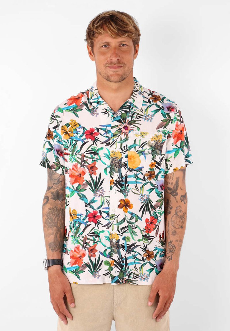 Chemise à manches courtes avec un fond rose pastel et un motif floral dense de couleurs variées. Devant à boutons et détail de poche poitrine.