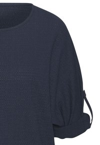 Top strutturato di un blu scuro con scollo rotondo, maniche ampie e polsini arrotolati fissati con bottoni. Design semplice e informale.