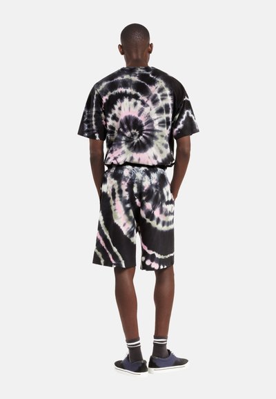 Sort tie-dye sæt bestående af en kortærmet skjorte og shorts med spiral mønstre i pink og grå. Materialet ser blødt ud, og pasformen er afslappet.