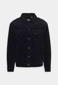 Veste en velours côtelé noire avec un col en peluche noir, deux poches avant avec rabats et fermeture à boutons sur le devant. Texture lisse avec des stries verticales.