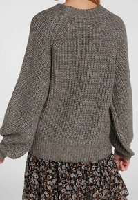 Szary dziergany sweter z teksturowanym wzorem, balonowymi rękawami i prążkowanym dołem. Tył ukazuje luźny krój i okrągły dekolt.