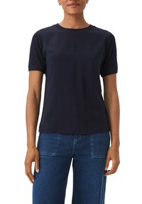 Navyblaues Baumwoll-T-Shirt mit kurzen Ärmeln, rundem Ausschnitt und lockerer Passform. Glatte Textur mit minimalem Design, kombiniert mit Denim-Hosen.