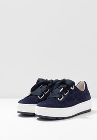 Sneakers in suede blu navy con suole spesse in gomma bianca, punta tonda e lacci blu oversized. Occhielli in metallo aggiungono dettagli al design.