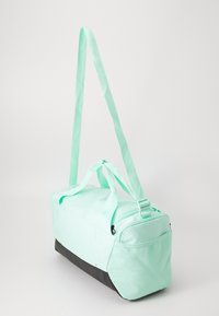 Mintgroene sporttas met een zwarte basis, verstelbare schouderbanden en een ritsvak. Glad materiaal met een gestructureerd ontwerp.