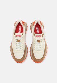 Sneaker bianchi e beige con accenti arancioni, caratterizzati da una combinazione di tessuto liscio e camoscio, suole текстurizzate e lacci prominenti.