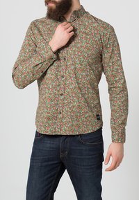 Lange mouw blouse met een bloemenpatroon in groene, roze en witte tinten. Knoopsluiting met een kraag en een gestructureerde stof.