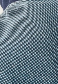 Tissu texturé avec un motif à carreaux bleu et blanc, doté d'une finition douce et d'une vue rapprochée du tissage.