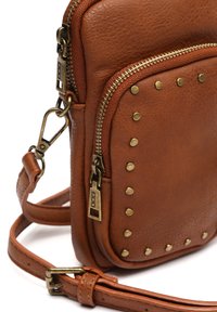 Brun läderhandväska med en textured finish, utrustad med detaljer i guldton, en zip-ficka och dekorativa nitar på framsidan.