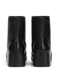 Botas de cuero negro hasta el tobillo con un diseño elegante, tacones bajos en bloque y un detalle de costura mínima en el borde superior.