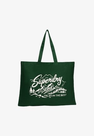 Bolsa de lona verde con dos asas, que presenta un diseño gráfico en blanco de montañas y árboles, con el texto "Superdry" encima.