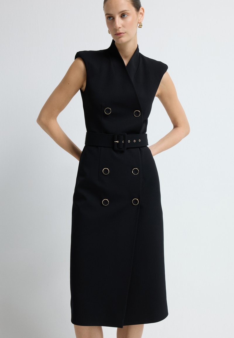 Czarna, bezrękawnikowa sukienka o kroju kopertowym, z podwójnymi złotymi guzikami, szerokim paskiem i spódnicą do kolan. Gładka tekstura.