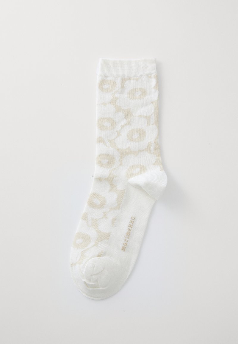 Calcetines blancos con un patrón floral en beige claro, con un puño acanalado y puntera reforzada. Nombre de la marca impreso en beige en el tobillo.
