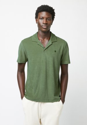 Grünes kurzärmliges Poloshirt mit einer weichen Textur, das über einen Kragen und ein kleines Baum-Logo auf der Brust verfügt.
