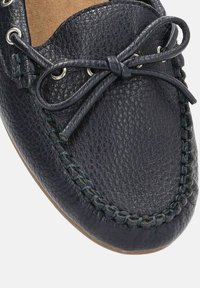 Mocasines de cuero azul marino con un acabado texturizado, que cuentan con un detalle de lazo y costuras decorativas a lo largo del borde. Forro interior suave.