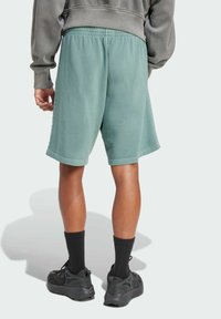 Grønne shorts lavet af blød stof, med en afslappet pasform, elastisk talje og sidesøm detaljer. Kombineret med sorte sokker og sko.
