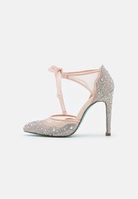 Scarpa con tacco alto in pelle verniciata rosa, con accenti traslucidi, decorata con strass, design a T-strap e dettagli a scallop.