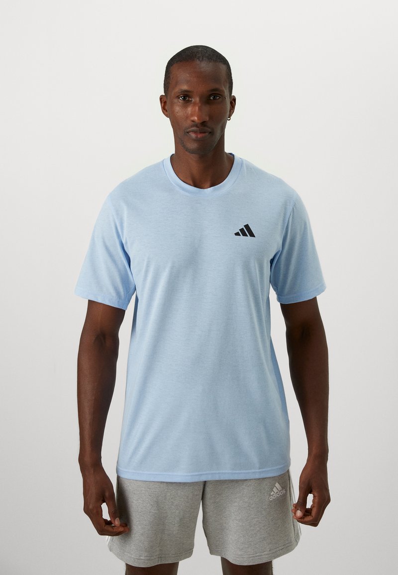 Lichtblauwe T-shirt met korte mouwen, gemaakt van zacht materiaal, met een zwart Adidas-logo op de linker borst. Naadloze kraag en een ontspannen pasvorm.