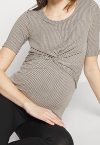 Grå ribbad mamma-topp med korta ärmar, med en knutdetalj vid midjan. Mjuk textilstruktur, figurnära design och rund halsringning.