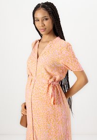 Pink patterned dress with a wrap style, short sleeves, and a tie at the waist. Features a swirl design in orange and lighter tones.
