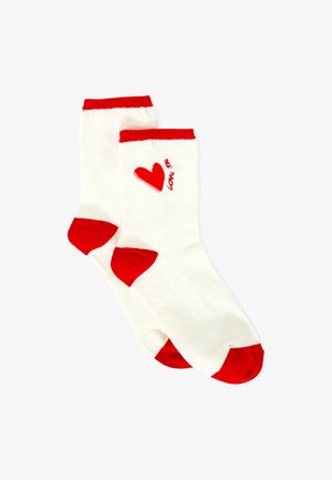 Weiße Baumwollsocken mit roten Akzenten, versehen mit einem roten Herzmotiv und dem Schriftzug "love me". Gerippter Bund sowie feste rote Fersen- und Zehenbereiche.