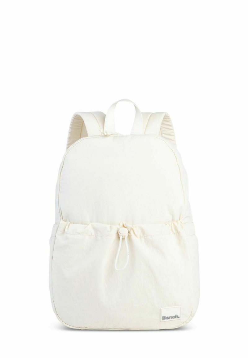 White fabric backpack with padded straps, rounded shape, cinch closure at the front pocket, and minimal branding tag at the bottom.