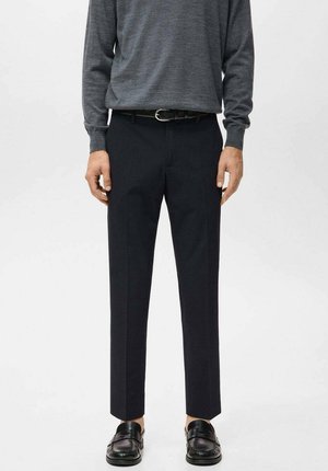 Pantaloni neri su misura con una vestibilità dritta. Realizzati in tessuto leggero, caratterizzati da una trama liscia e da una sottile lucentezza, abbinati a una maglia grigia.